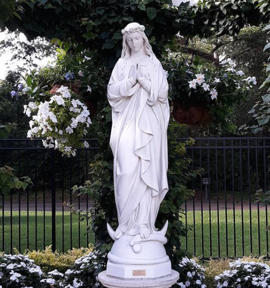 Large outdoor Mary statue in grotto on church grounds